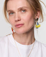Close-up of a person wearing colorful earrings against a neutral background