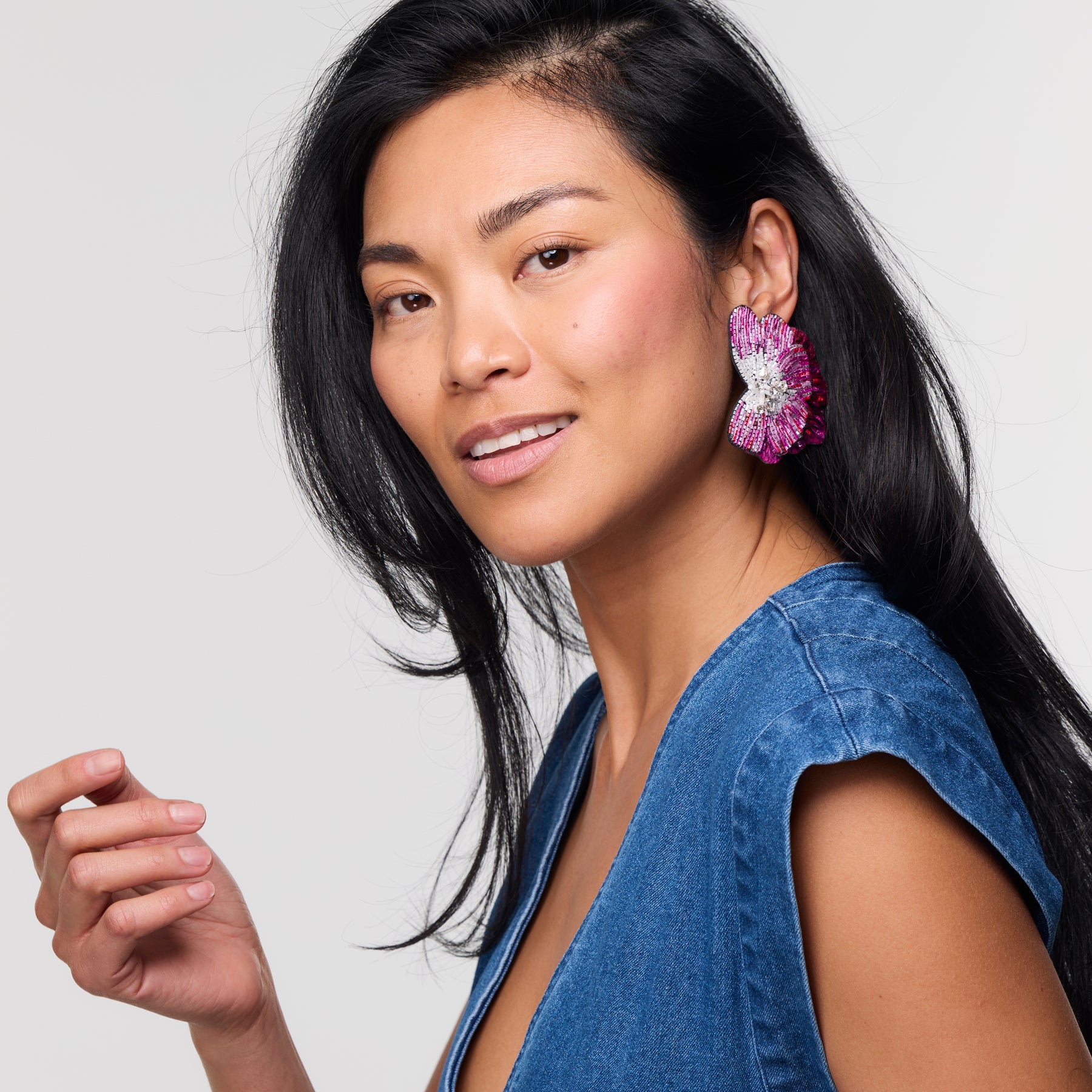 Woman wearing a colorful and embroidered floral shaped earring against a white background