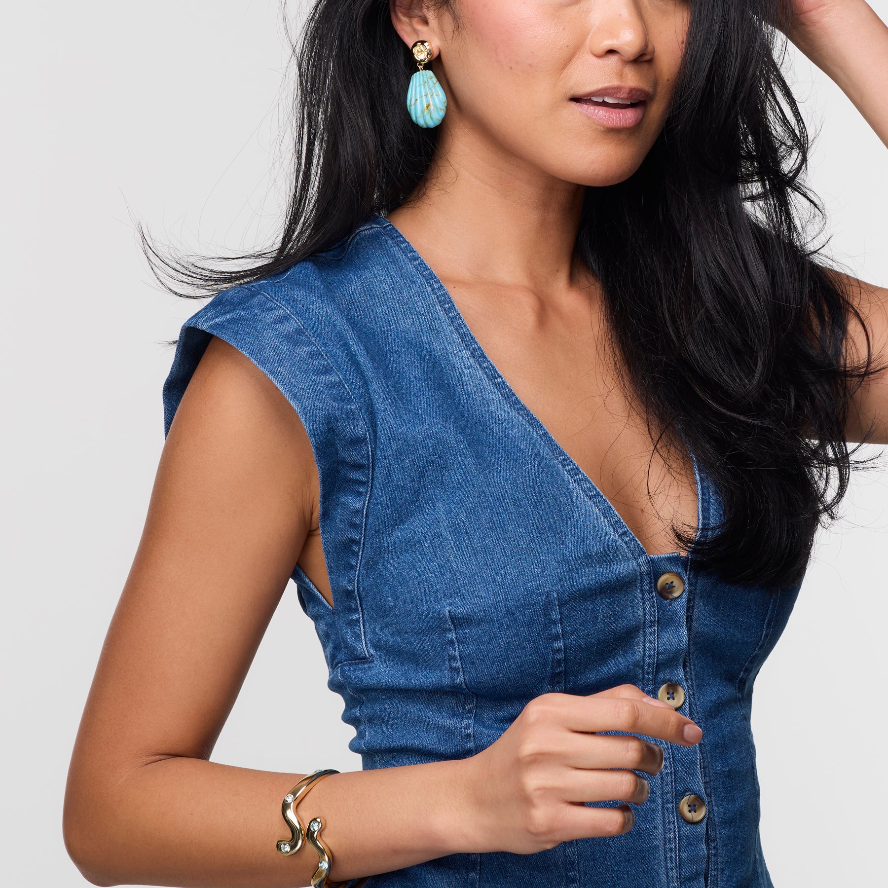 Woman wearing a blue denim dress with a plain background