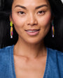 Woman wearing colorful earrings with a neutral background