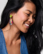 Woman wearing colorful earrings with a neutral background