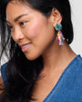 Woman wearing colorful earrings with a plain background