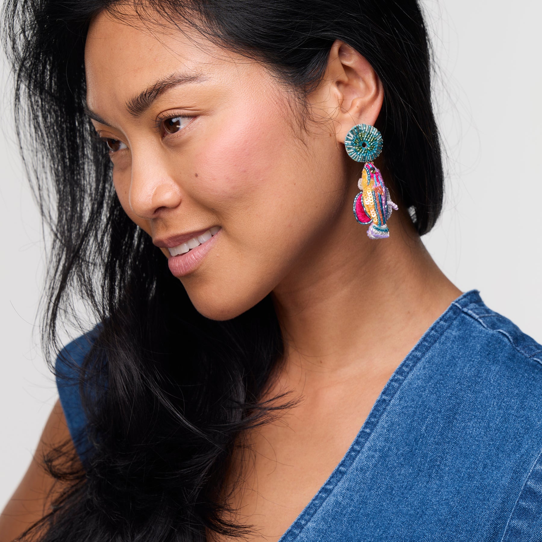 Woman wearing colorful earrings with a plain background