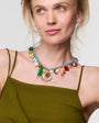 Woman wearing a colorful shell shaped Necklace in green dress  against a white background