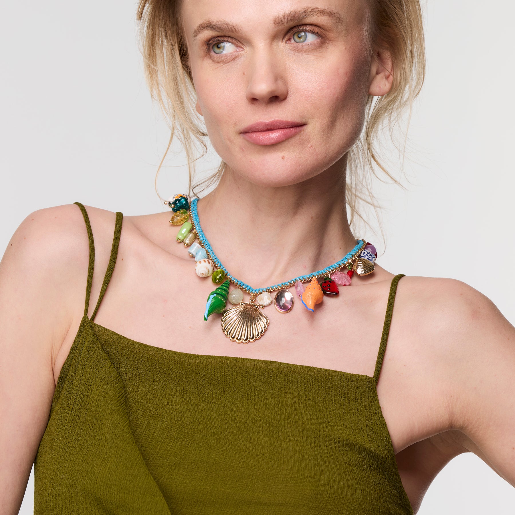 Woman wearing a colorful shell shaped Necklace in green dress  against a white background