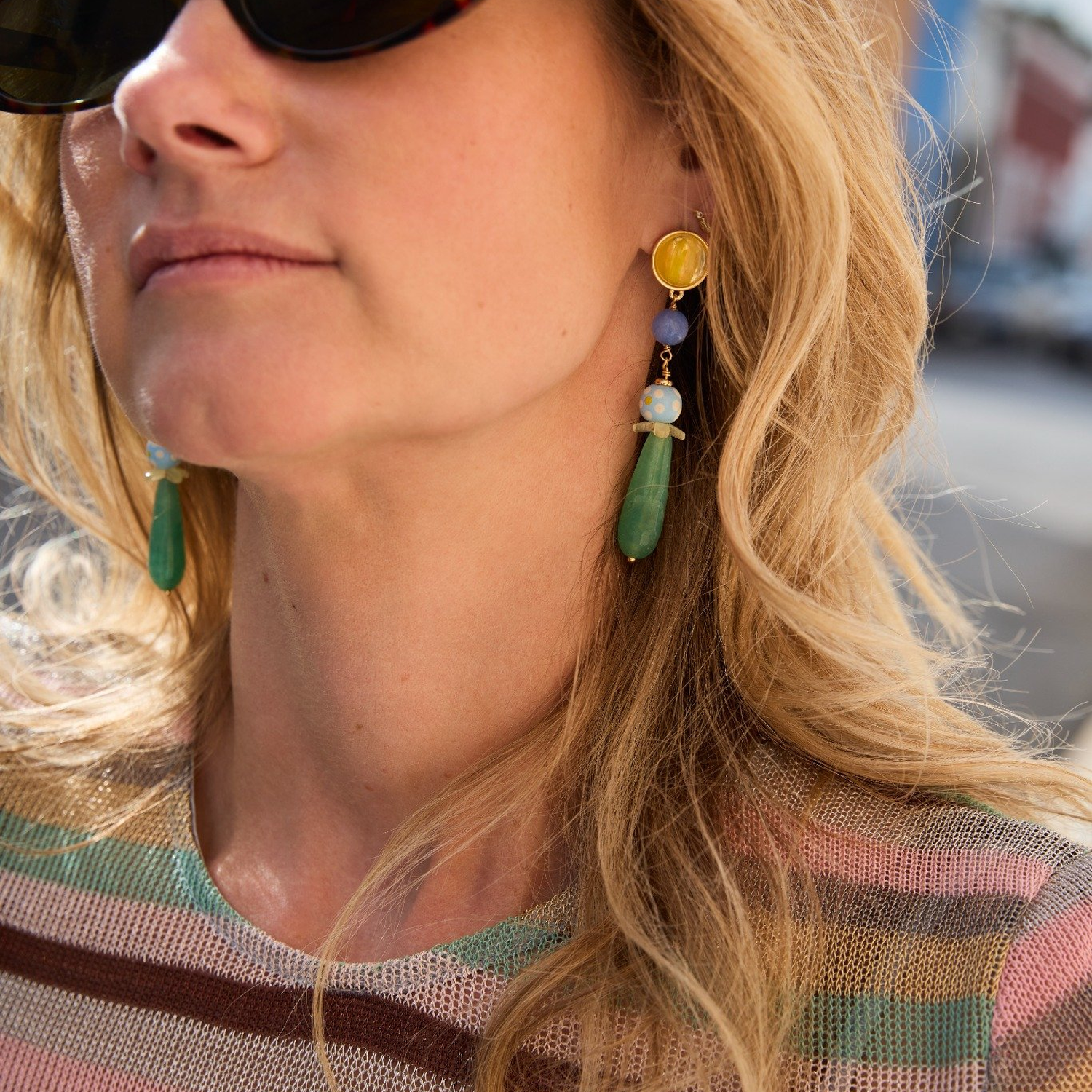 Close-up of a woman wearing colorful earrings with a blurred background