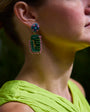 Model Wearing Leslie Earrings against dark background in yellow dress. 