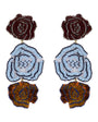 A pair of beaded drop earrings with three floral layers each. The top layer is a dark maroon rose, the middle layer is a light blue and white rosette with black accents, and the bottom layer is a golden-brown rose with blue and black detailing.