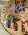 Multiple embroidered and gold earrings laid against wicker basket