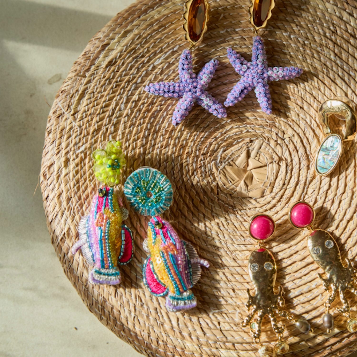 Multiple embroidered and gold earrings laid against wicker basket