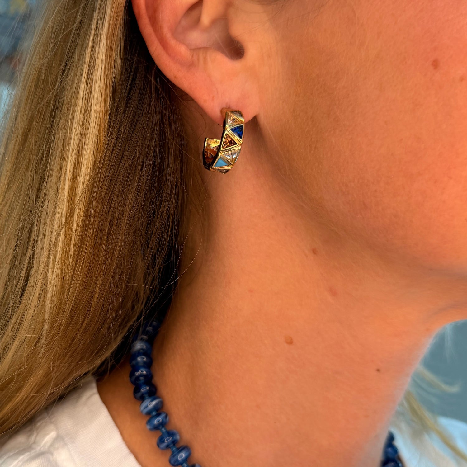 Model wearing gold and sapphire hoop earrings
