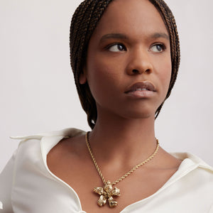 Gold Flower Pendant Necklace Styled on Model in White Shirt