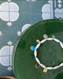 Bracelet with gemstones on a green cushion against a patterned tile background