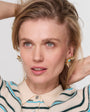 Model wearing gold starburst earrings with turquoise center