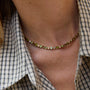 A woman wearirng a green and brown colored tennis necklace in a plaid shirt