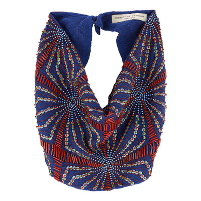 A blue beaded cowl neck scarf with red and gold geometric patterns, featuring a knotted back detail and a visible 'MIGNONNE GAVIGAN' brand label.