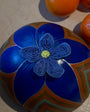 Decorative blue ball with a floral design on a light surface with oranges.