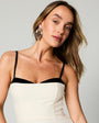 Model wearing hand crafted and embroidered earrings shaped like a floral with a white and black strappy tank top