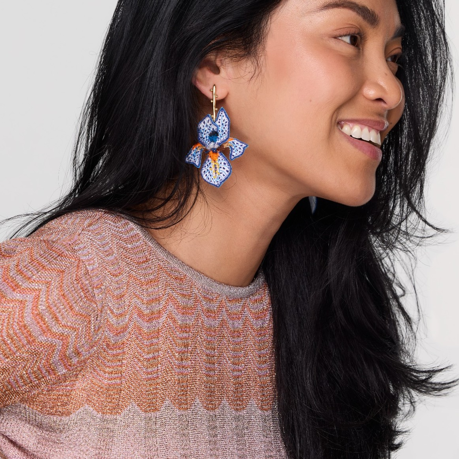 Woman wearing blue floral earrings with a neutral background