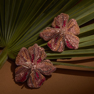Beaded Pink and Gold Flower Earrings Staged on Palm Leaf and Brown Surface