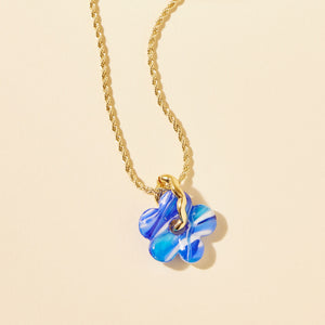 Blue and White Marbled Glass Flower Charm Pendant Gold Chain Necklace on Flat Cream Background