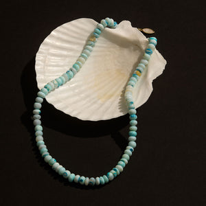 Blue Beaded Strand Necklace Shown On White Shell and Black Background