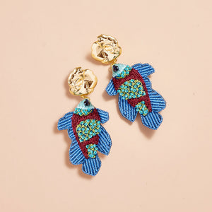 Blue, Green, and Brown Beaded and Embroidered Fish Drop Earrings with Gold Top on Tan Background