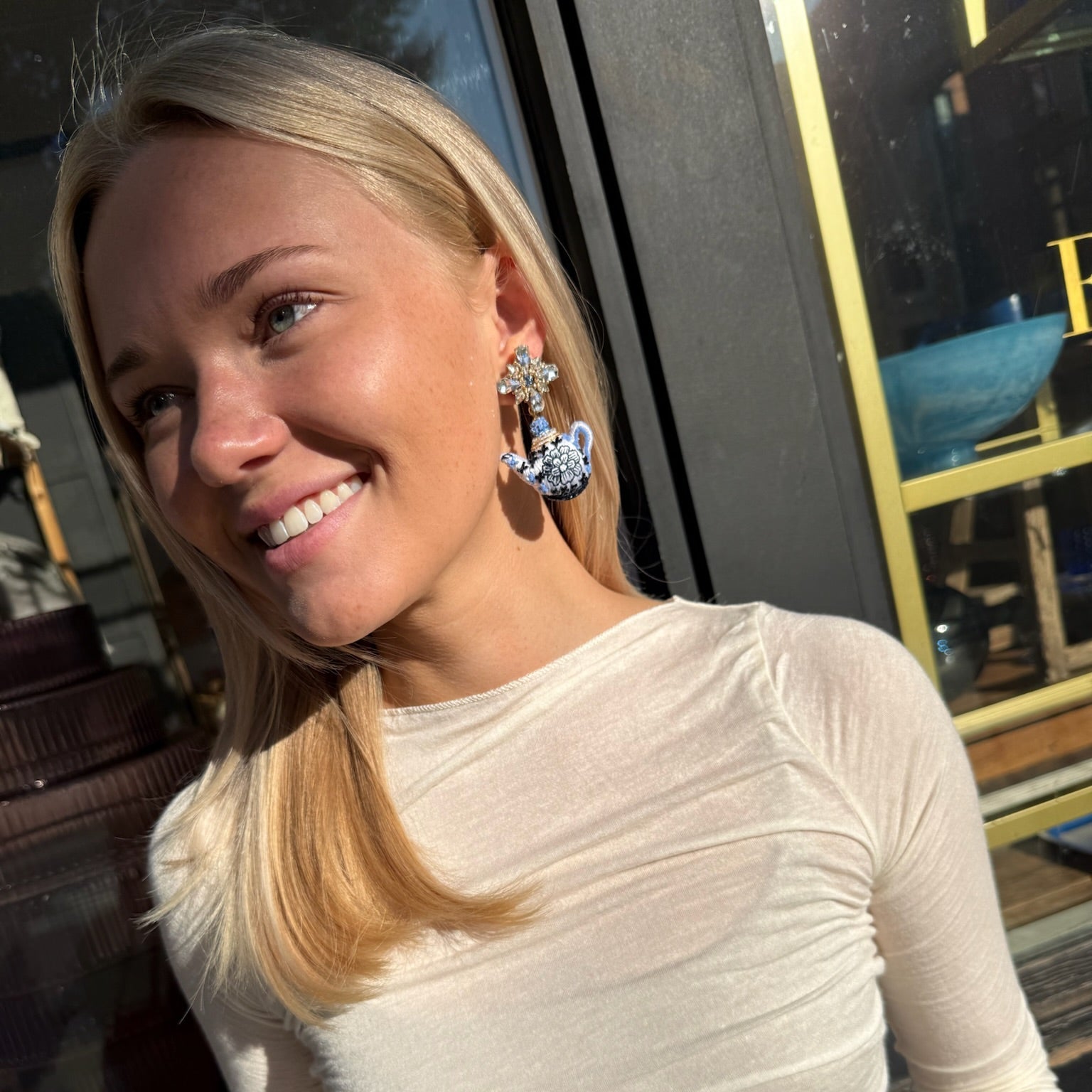 Woman wearing white shirt and teapot earrings