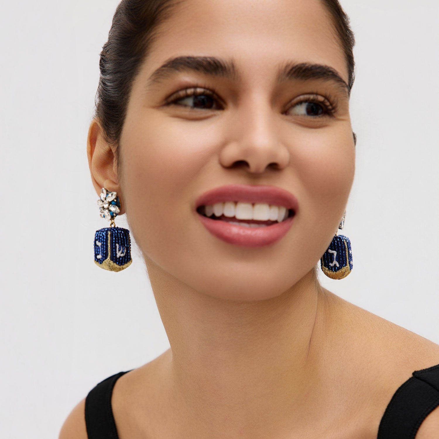 Beaded dreidel drop earrings styled on model in black top with white background