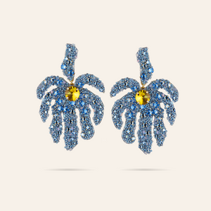 Blue Beaded and Embroidered Palm Leaf Drop Earrings with Yellow Crystal Center on Tan Background