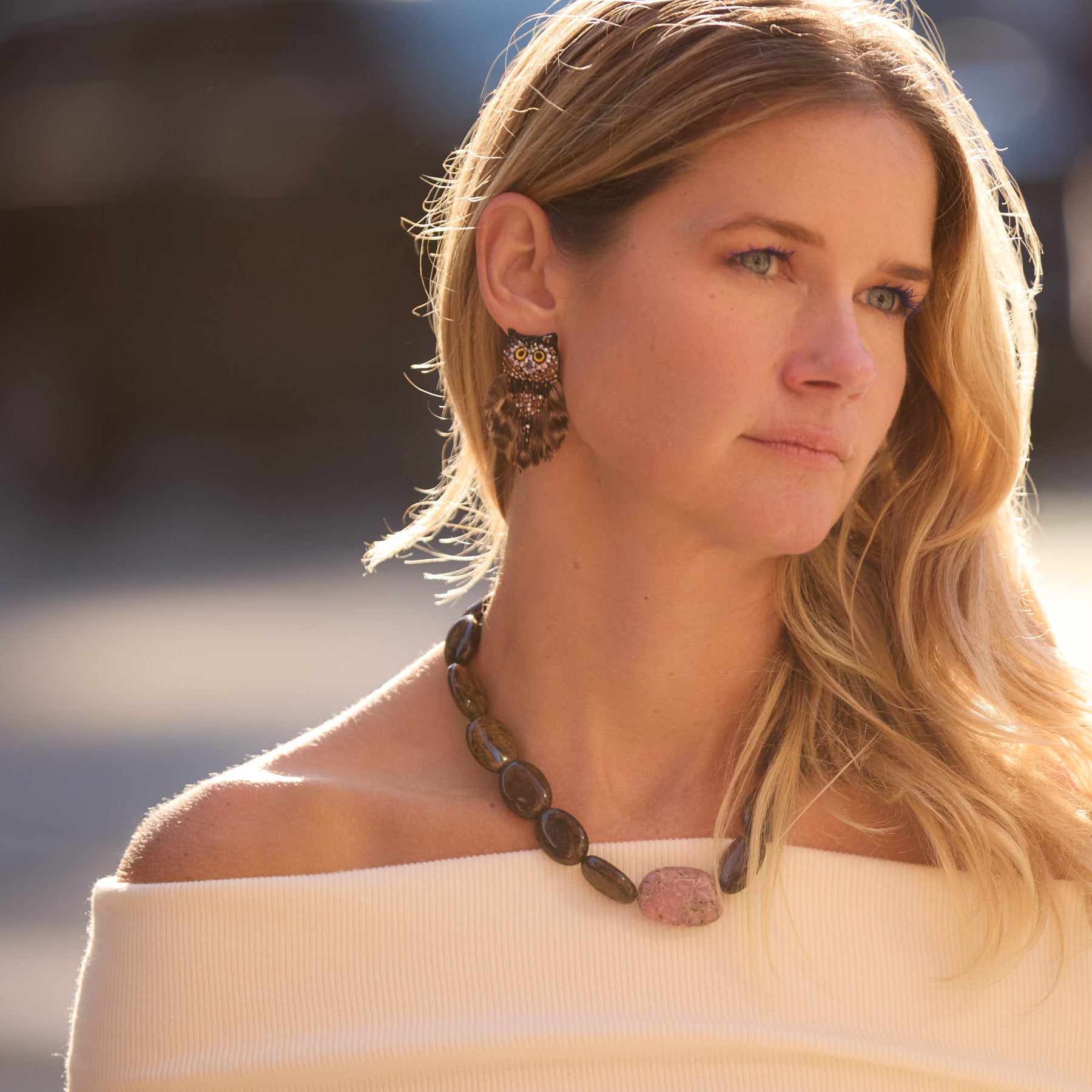 Maggie wearing brown owl stud earrings and stone necklace