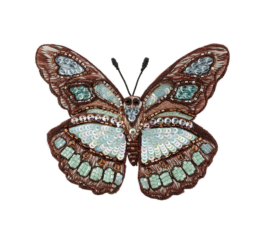 Decorative butterfly brooch with sequin details on a white background