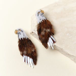 Brown and White Feather and Bead Eagle Stud Earrings on Tan Background