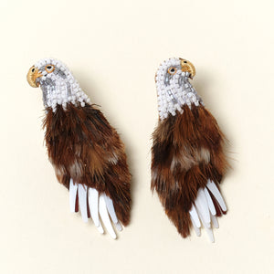 Brown and White Feather and Bead Eagle Stud Earrings on Tan Background