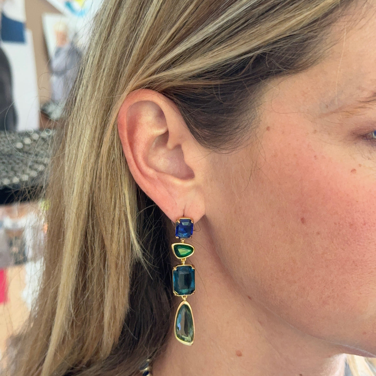 Gold-tone drop earrings featuring blue, teal, and clear faceted stones in a layered geometric design on Mignonne Gavigan close up