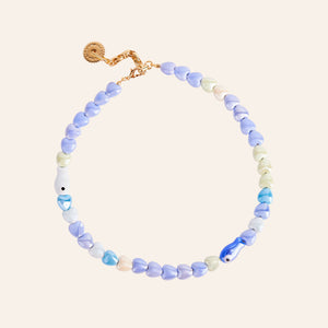 Blue and White Beaded Fish and Heart Necklace on Tan Background
