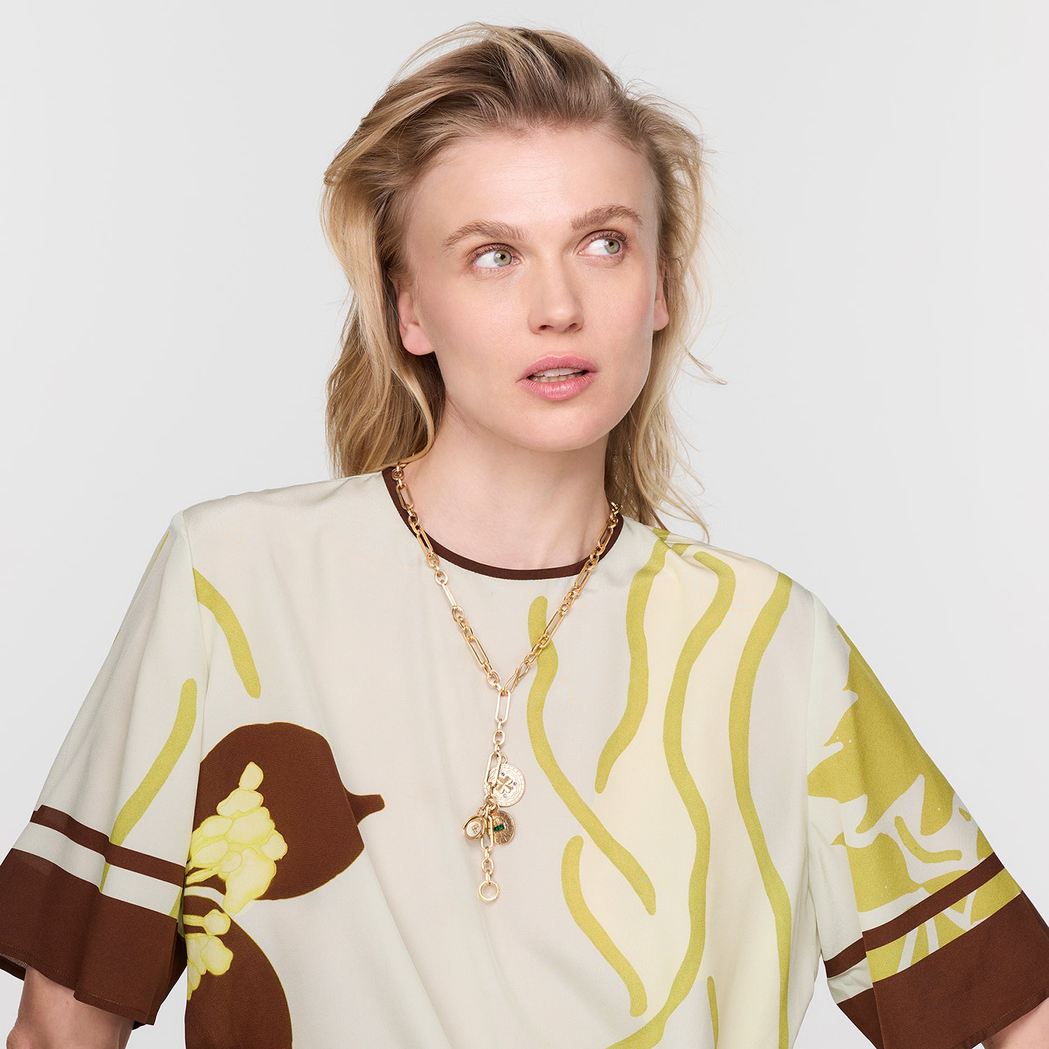 Model wearing gold chain charm necklace on white background