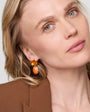 Woman wearing colorful orange drop stone earrings with a neutral background