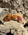 Gold earrings with gemstones on a textured stone surface