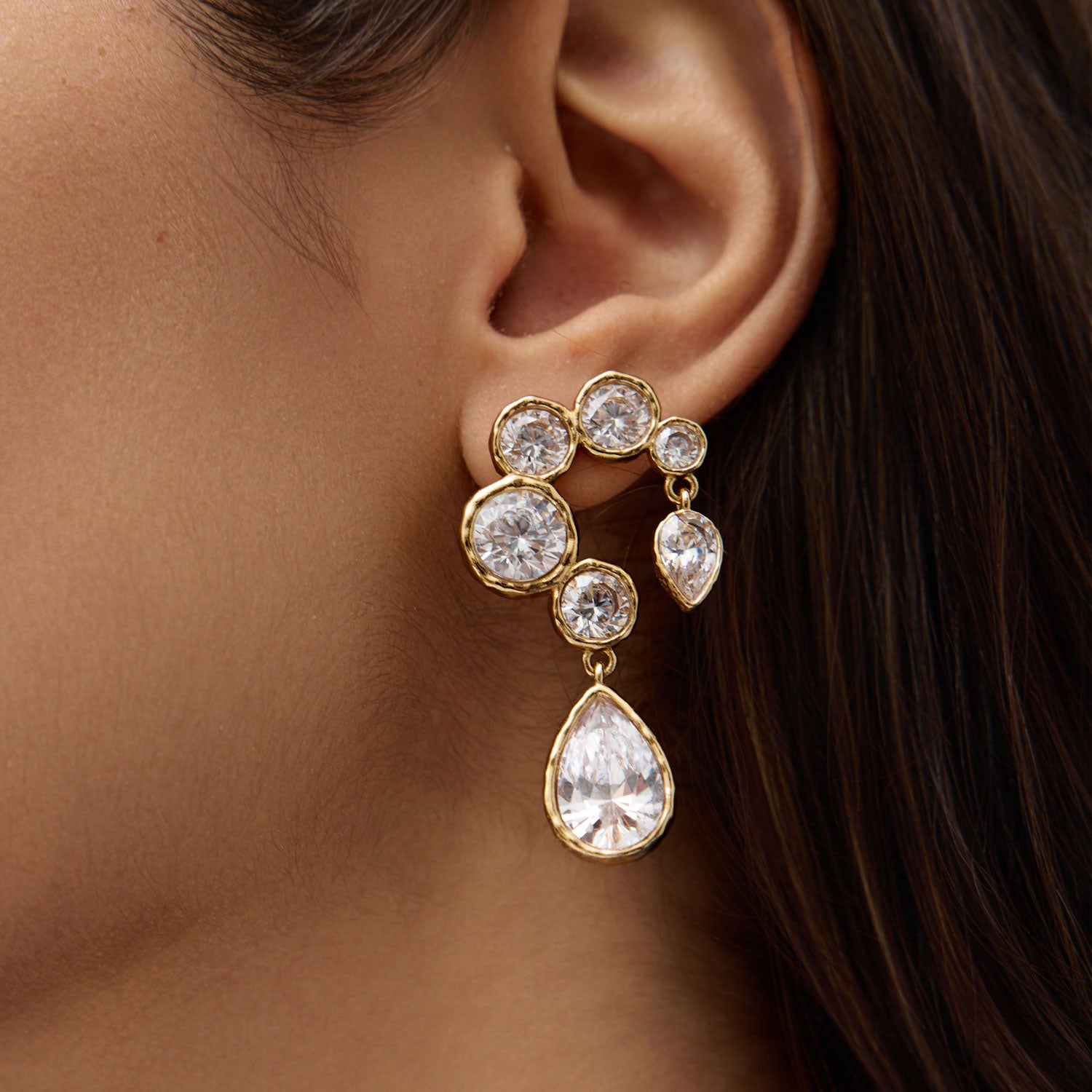 Close up of woman wearing crystal and gold drop earrings