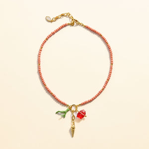 Coral Enamel Beaded Necklace with Fish, Coral, and Shell Charm on Tan Background