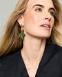 Mode wearing pineapple shaped earrings with beaded and embroidered crafted elements