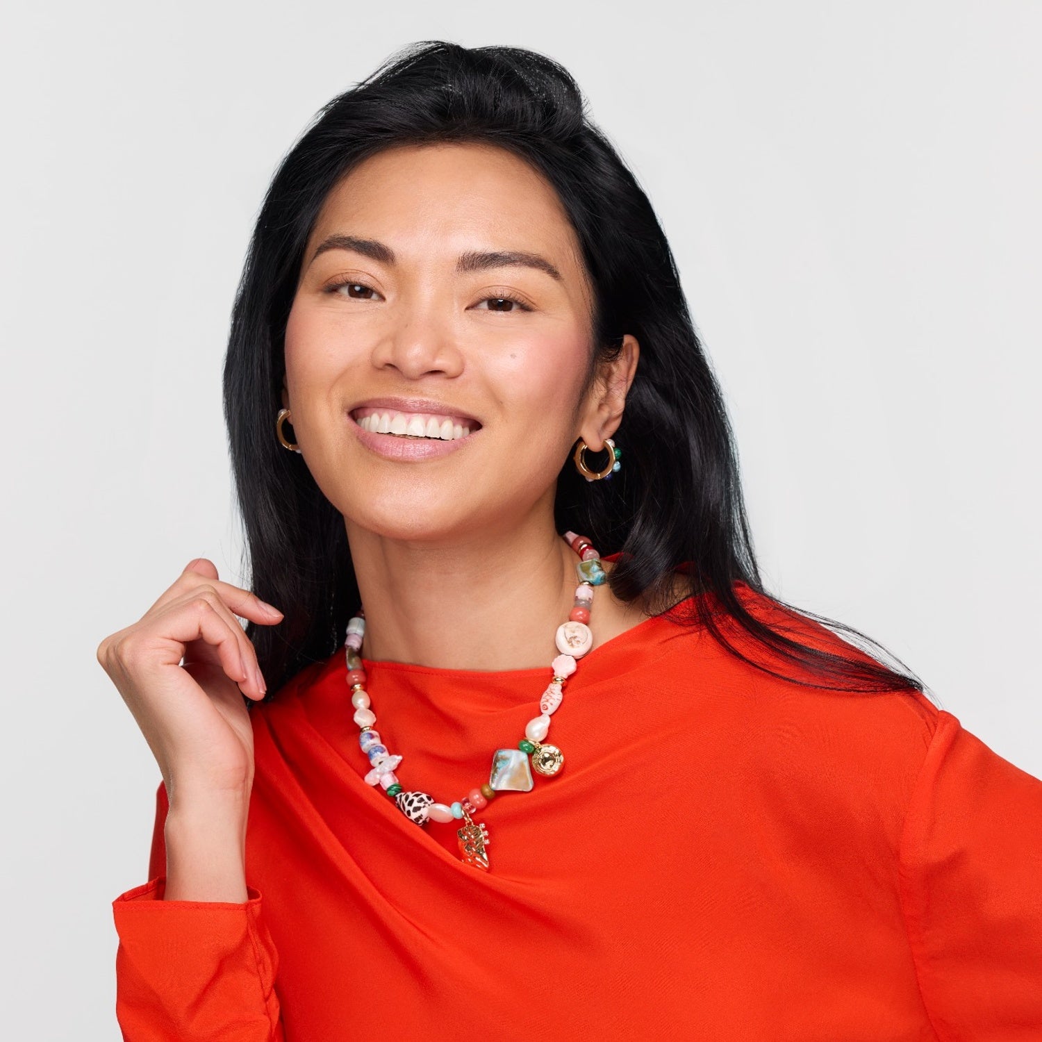 Woman wearing a colorful necklace against a plain background