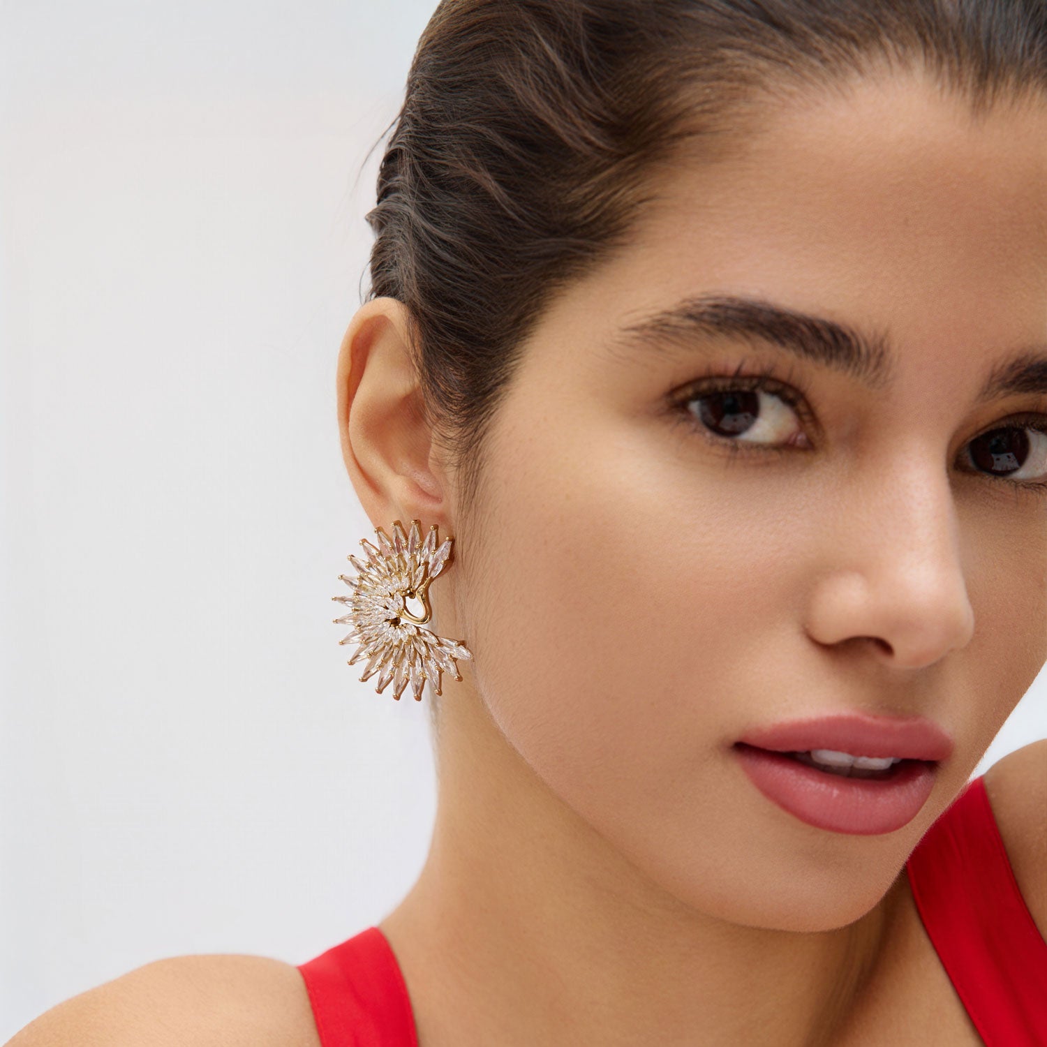 Woman wearing red dress and crystal stud earrings with white background