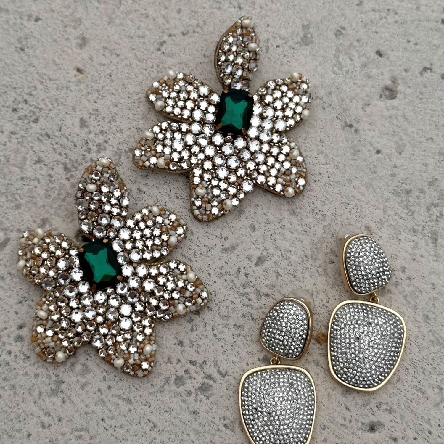 Crystal Double Drop Earrings and Clear and Emerald Crystal Statement Flower Earrings on Marble Background