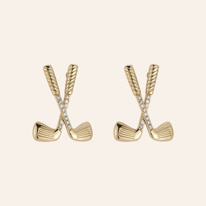 Gold golf club-shaped earrings with clear stones on a beige background