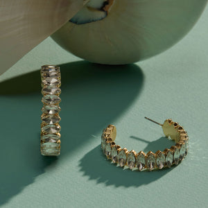 Crystal and Gold Hoop Earrings Staged with Shell on Green Surface