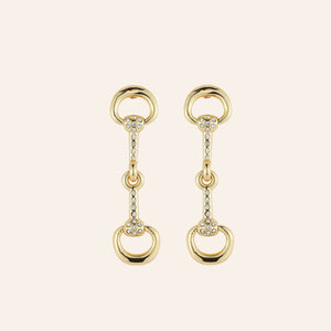 Gold and Crystal Horse Bit Drop Earrings on Tan Background