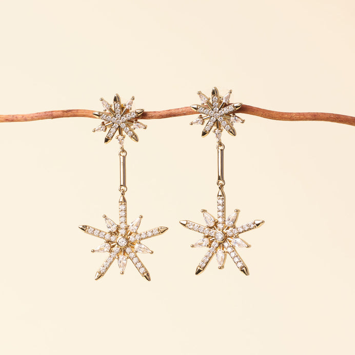 Gold and Clear Crystal Star Double Drop Earrings Staged on Branch with Tan Background