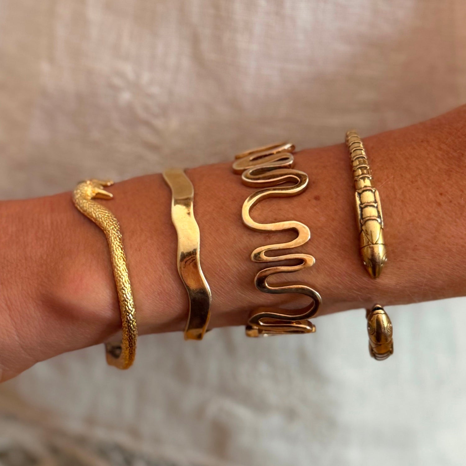 Model arm wearing stack of bangles on beige background
